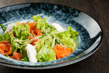 Greek salad of tomatoes, pickled peppers, cucumbers, lettuce and feta cheese. greek salad with olives and white sesame seeds on a blue marble plate