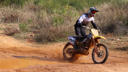 Obraz premium Professional dirt bike motocross rider performing stunts in extreme mud terrain track