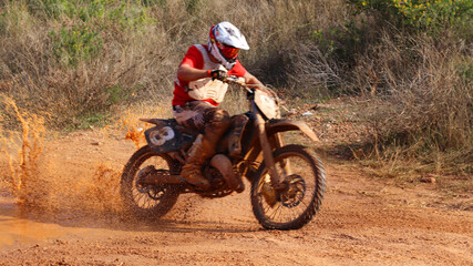 Fototapeta na wymiar Professional dirt bike motocross rider performing stunts in extreme mud terrain track