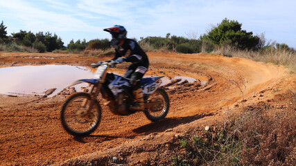 Obraz premium Professional dirt bike motocross rider performing stunts in extreme mud terrain track