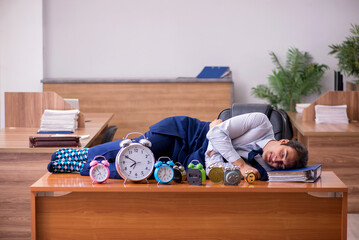 Young male employee sleeping in the office in time management co