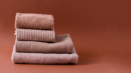 Fototapeta na wymiar A stack of cotton clean brown-hued towels on a brown background.
