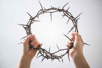 two hands hold crown of thorns , isolated on white background