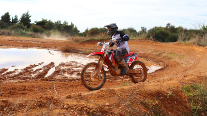 Fototapeta na wymiar Professional dirt bike motocross rider performing stunts in extreme mud terrain track