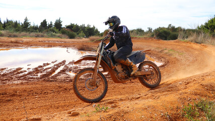 Professional dirt bike motocross rider performing stunts in extreme mud terrain track