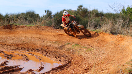 Professional dirt bike motocross rider performing stunts in extreme terrain track