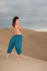 Arab belly dancer in the desert at sunset