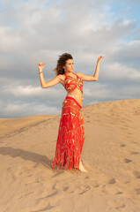 Arab belly dancer in the desert at sunset