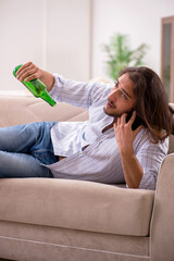 Young man drinking alcohol at home