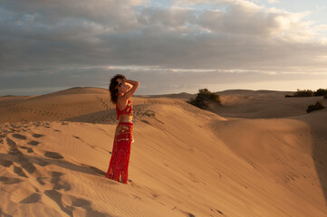 Arab belly dancer in the desert at sunset