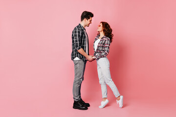 Girl in white pants holding hands with boyfriend. Studio full length shot of romantic couple.