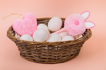 Fototapeta na wymiar Easter. White eggs in a basket on a uniform pink background. Place for text.