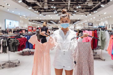 Young woman shopping apparels in clothing boutique with protective face mask
