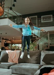 Foto op Canvas Cute, joyful child jumping on te couch © konradbak