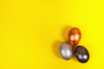 Multi-colored eggs on a uniform yellow background with place for text.