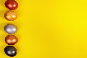 Multi-colored eggs on a uniform yellow background with place for text.