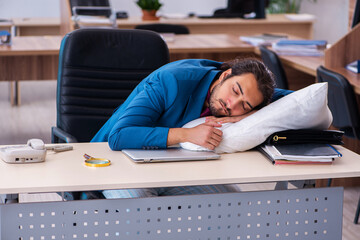 Young male employee coming to work straight from bed