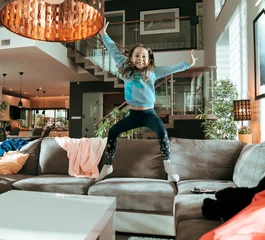 Foto op Canvas Cute, joyful child jumping on te couch © konradbak