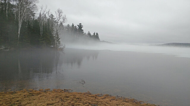 Mist over a melting lake in spring on a grey day