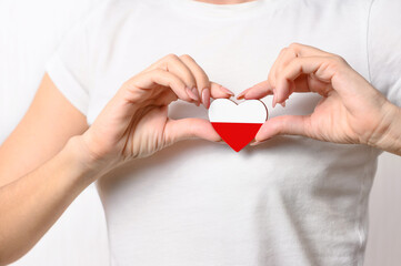 Love Poland. The girl holds a heart in the form of the flag of Poland on her chest. Polish...