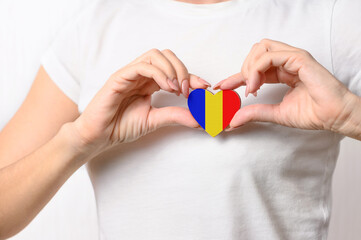Love Romania. The girl holds a heart in the form of the flag of Romania on her chest. Romanian patriotism concept