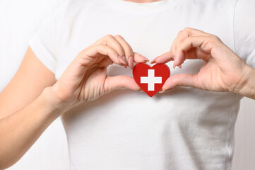 Love Switzerland. The girl holds a heart in the form of the flag of Switzerland on her chest. Swiss patriotism concept
