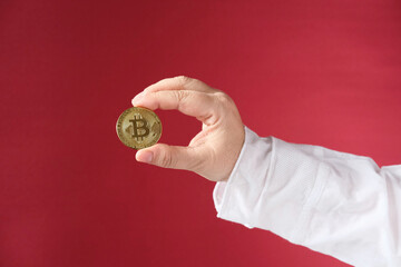 female hand holds gold bitcoin, red background, sale charts, up and down concept, banking, saving money