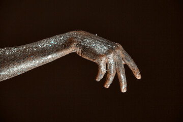 Silver sparkling body art, close up of female hand, woman's arm in sparkles, skincare concept