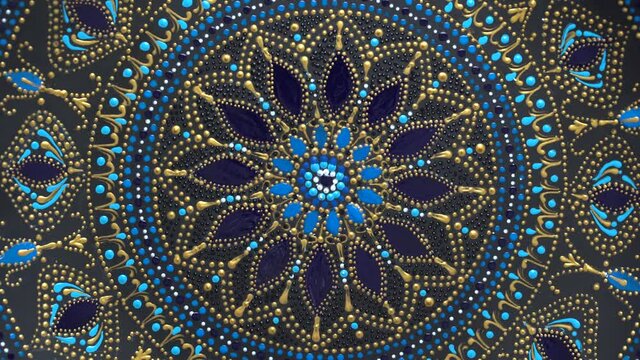 Decorative ceramic plate with black, blue and golden colors, painted plate on background, closeup, top view, rotate. Decorative porcelain plate painted with acrylic paints, handwork, dot painting
