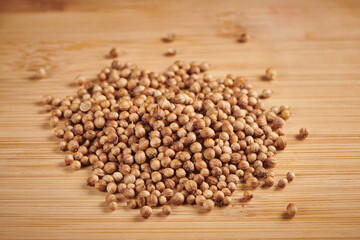 Heap of dry coriander seeds on a wooden background. Close up view.