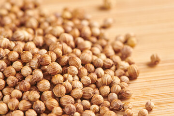Heap of dry coriander seeds on a wooden background. Close up view.