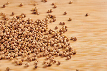 Heap of dry coriander seeds on a wooden background. Close up view.