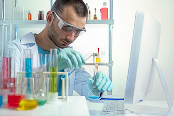 Chemistry laboratory assistant in protective goggles mixing liquids in laboratory glassware