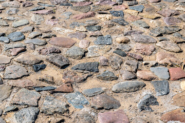 The texture of an ancient road with paving stones. Natural stone texture Close-up of an ancient paved road.