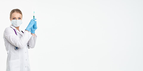A young nurse in a mask and white coat holds a syringe with a needle for injections, flu shots, covid. The concept of vaccination and protection against influenza, from a pandemic. copy space. banner