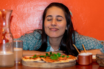 joven degustando una pizza, mujer comiendo pizza, mujer oliendo comida con placer
