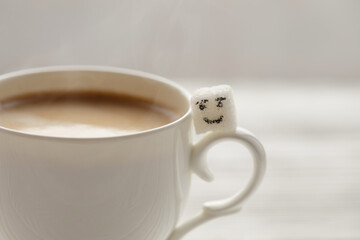 White sugar cube on cup of coffee. Smile. Concept.