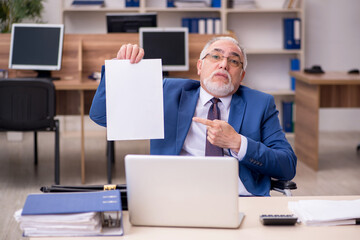 Old businessman employee in wheel-chair working in the office