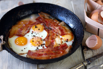 Scrambled eggs with bacon in a frying pan. Traditional delicious breakfast. Juicy appetizing scrambled eggs with bacon.