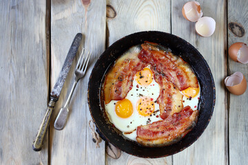 Scrambled eggs with bacon in a frying pan. Traditional delicious breakfast. Juicy appetizing scrambled eggs with bacon.