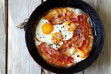 Scrambled eggs with bacon in a frying pan. Traditional delicious breakfast. Juicy appetizing scrambled eggs with bacon.