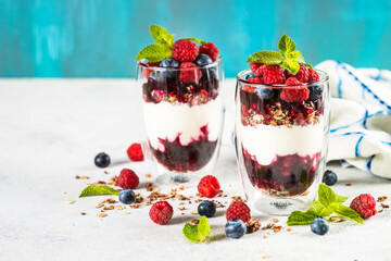 Parfait with yogurt, granola, jam and fresh berries in the glass jar. Healthy dessert or snack.