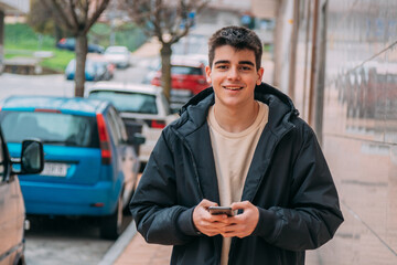 smiling teenager or student with mobile phone on the street