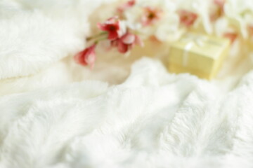 Present box and flowers in bed, small yellow  gift and sakura blooming in white fluffy bedding blanket, love surprise 