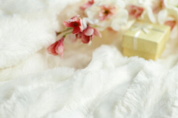 Present box and flowers in bed, small yellow  gift and sakura blooming in white fluffy bedding blanket, love surprise 