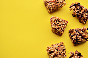 Pieces of granola bar on a yellow background on the right side of the photo view from above with a copy space. High quality photo