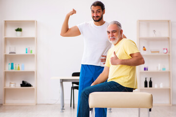 Obraz premium Old male patient visiting young male doctor chiropractor