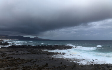 Gran Canaria, view towards the main body of the island from El Confital beach on the edge of Las Palmas de Gran Canaria, rain sweeping through the island
