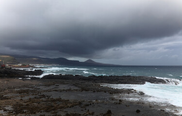 Gran Canaria, view towards the main body of the island from El Confital beach on the edge of Las Palmas de Gran Canaria, rain sweeping through the island
