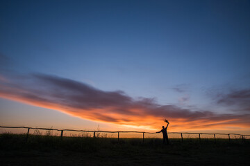 Silhouette of a man with a bouquet on the background of dawn.